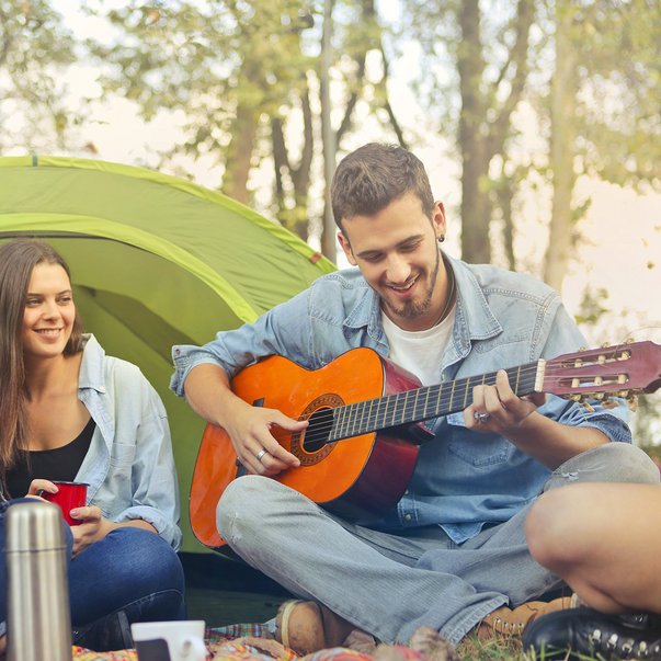 Jugendliche beim Zelten mit Gitarre