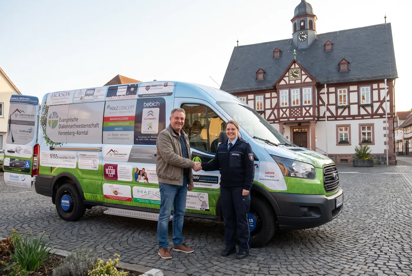 Ein neu ausgestattetes Kommunalfahrzeug mit dezenter Werbefläche parkt vor einem Gemeindegebäude, im Hintergrund ein Team von Mitarbeitenden von hinten beim Beladen, freundliches Tageslicht.